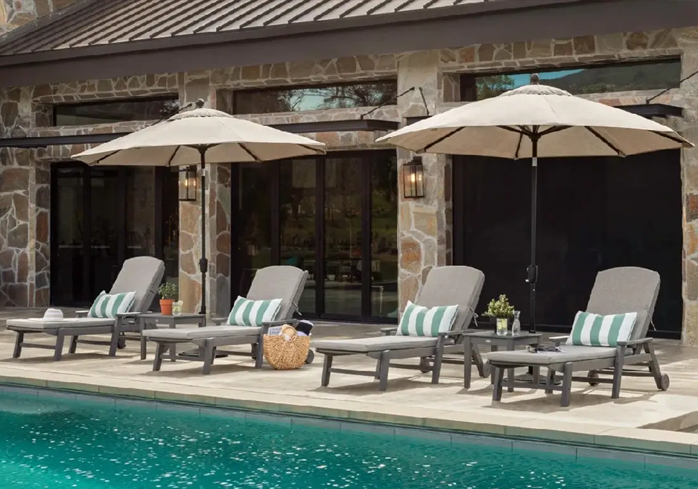 Luxury pool deck featuring cushioned commercial Nautical chaise lounges and large market umbrellas creating a relaxing resort-style retreat.